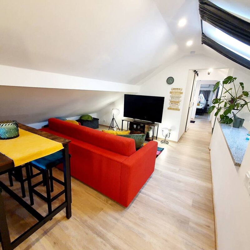 Bright living area with red sofa & TV – 3-room apartment for short-term rental in Puch, temporary housing 1–6 months