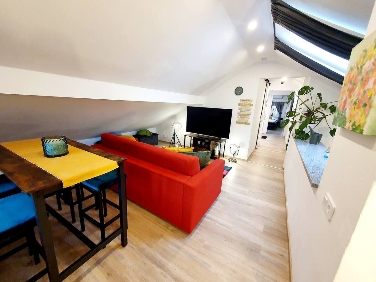 Bright living area with red sofa & TV – 3-room apartment for short-term rental in Puch, temporary housing 1–6 months
