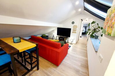 Bright living area with red sofa & TV – 3-room apartment for short-term rental in Puch, temporary housing 1–6 months
