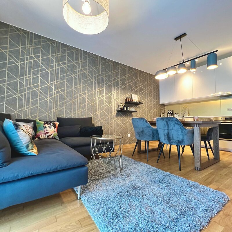 Wohnzimmer mit Sofa, Esstisch und TV