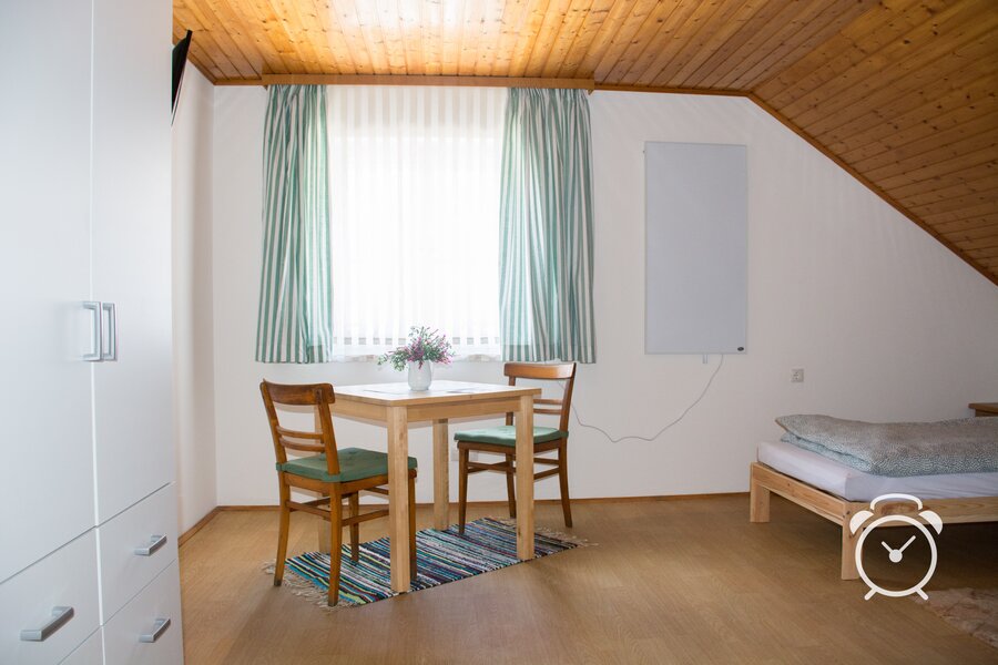 Bright room with wood ceiling & dining table – guesthouse short-term rental & temporary housing for 1 to 6 months in St. Georgen