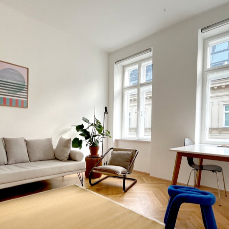 Helles Wohnzimmer mit Sofa & Arbeitsplatz – 1-Zimmer Wohnung zur Kurzzeitmiete & Wohnen auf Zeit für 1 bis 6 Monate in Wien | © Patrizia Zobernig