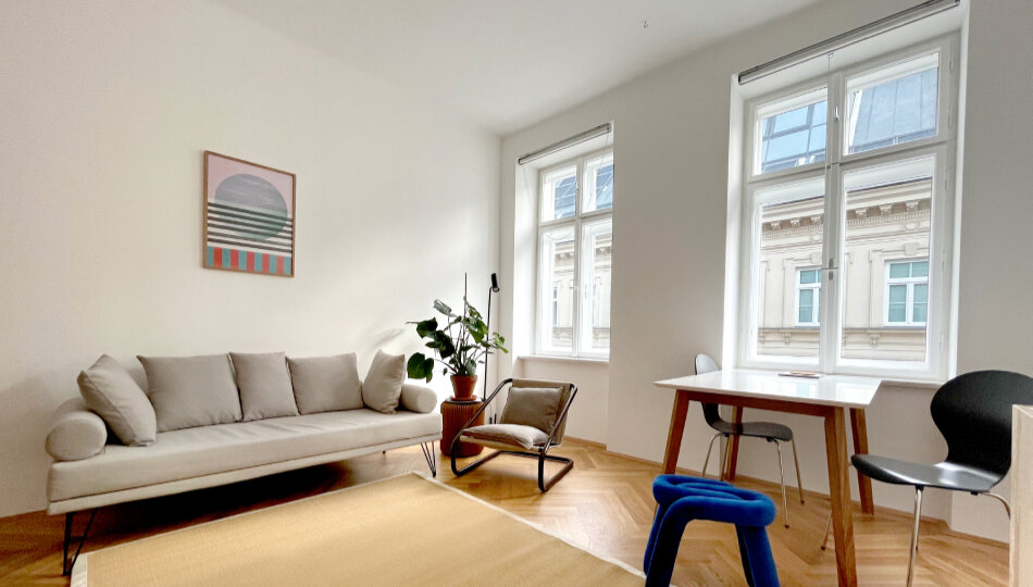 Helles Wohnzimmer mit Sofa & Arbeitsplatz – 1-Zimmer Wohnung zur Kurzzeitmiete & Wohnen auf Zeit für 1 bis 6 Monate in Wien | © Patrizia Zobernig