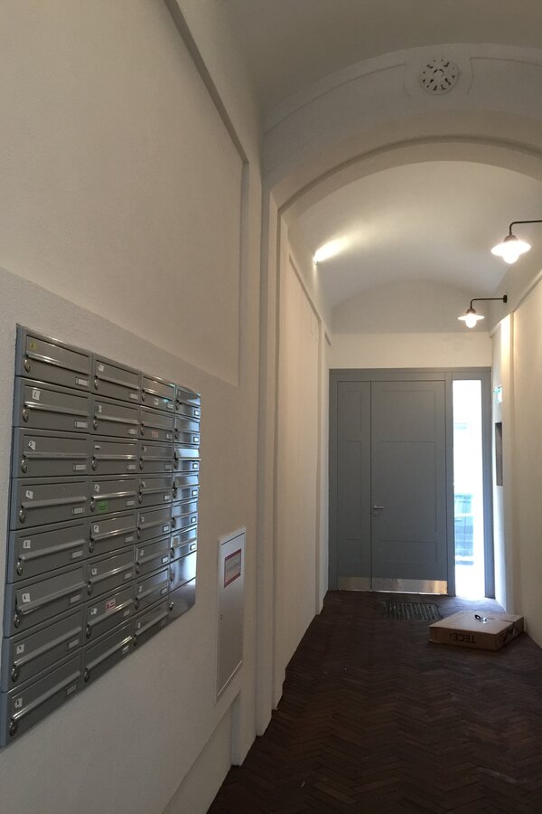 Eingangsflur zum Innenhof mit mit automatischen Flurlampen und Briefkästen | © Jeanne Szilit