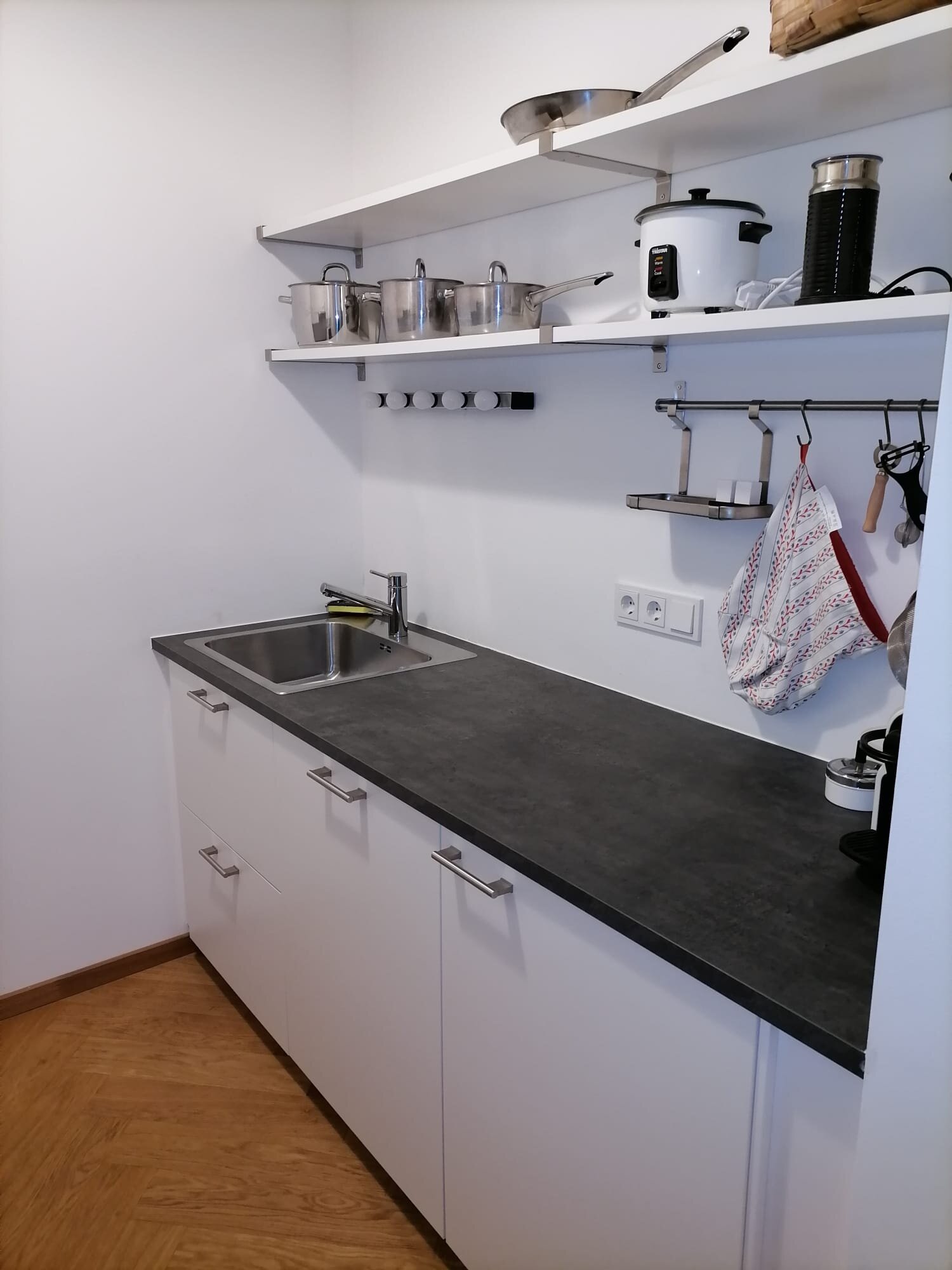 Küchenzeile rechts mit Waschbecken, Geschirrspüler, Kühlschrank, Küchenregal und Kochutensilien | © Jeanne Szilit