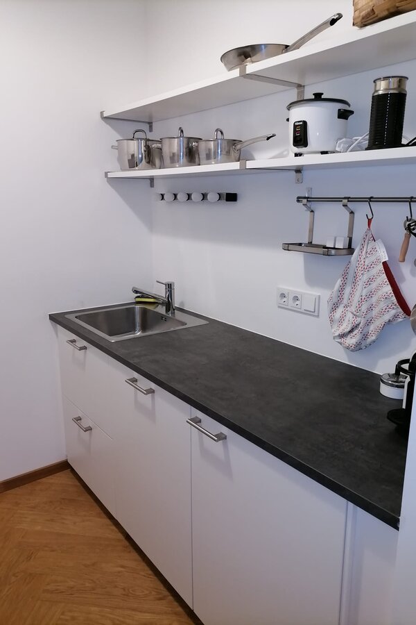 Küchenzeile rechts mit Waschbecken, Geschirrspüler, Kühlschrank, Küchenregal und Kochutensilien | © Jeanne Szilit