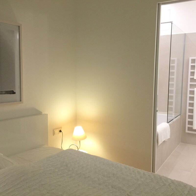Schlafzimmer mit Nachttischlampe und Badezimmer-Zugang | © Jeanne Szilit