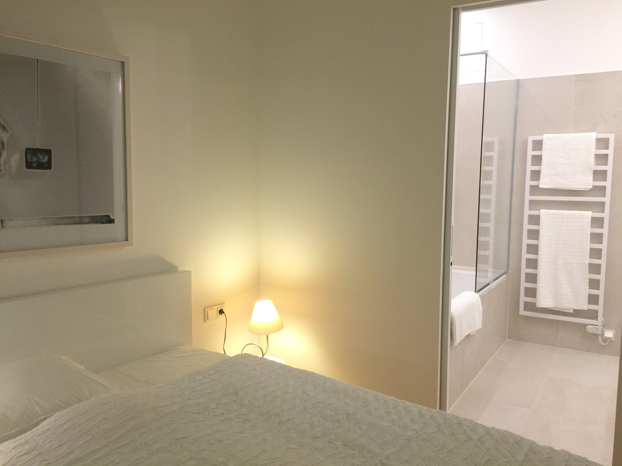 Schlafzimmer mit Nachttischlampe und Badezimmer-Zugang | © Jeanne Szilit