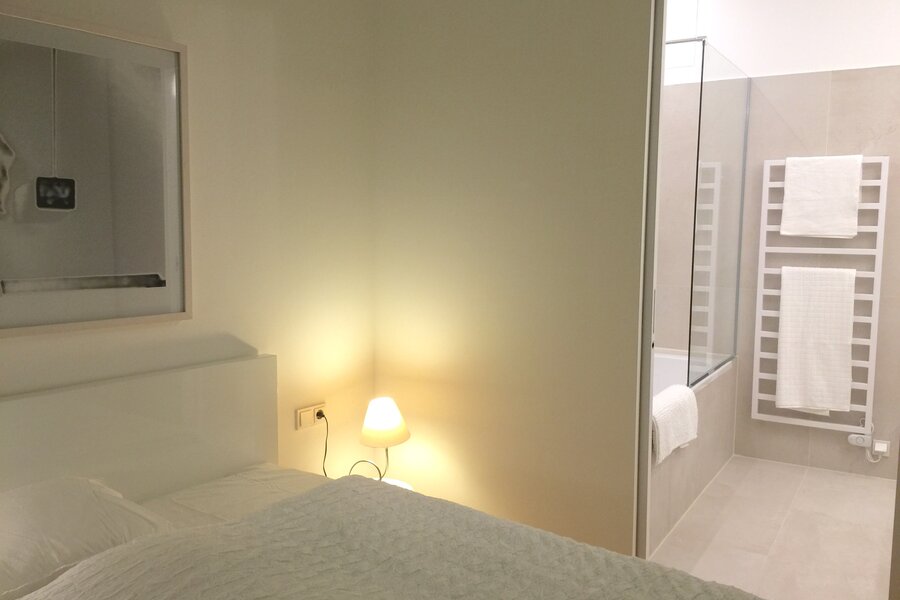 Schlafzimmer mit Nachttischlampe und Badezimmer-Zugang | © Jeanne Szilit