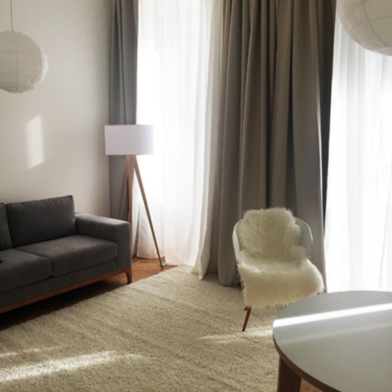 Wohnzimmer mit Sofa, Stehlampe, Stuhl, Fenster und separater Balkontür | © Jeanne Szilit