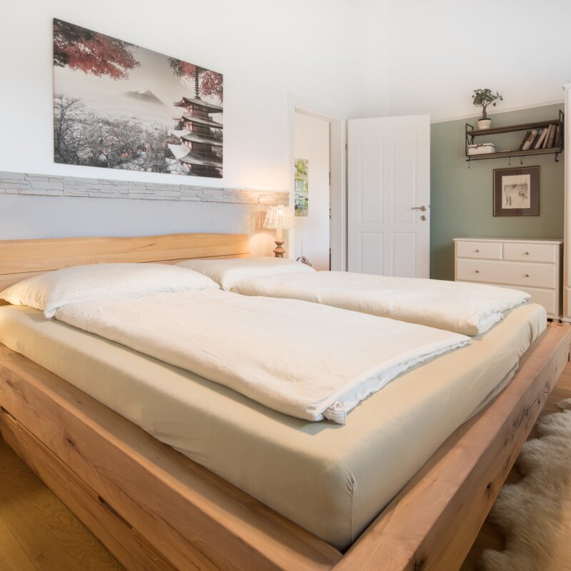 The 17m² room is equipped with a spacious wardrobe and a large, comfortable bed with a high-quality natural rubber mattress. This arrangement cannot be changed.  The white mirror cabinet on the left can be moved if necessary to make room for a desk, additional dining table, or other preferences. (Alternative furniture is available or can be brought along). The room has its own access to the roof terrace.