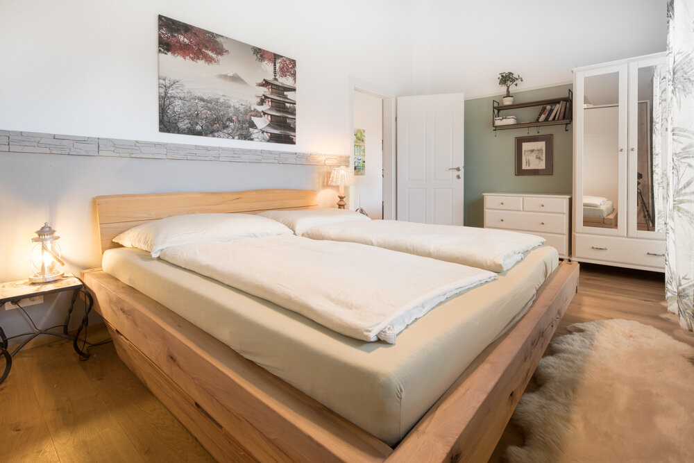 The 17m² room is equipped with a spacious wardrobe and a large, comfortable bed with a high-quality natural rubber mattress. This arrangement cannot be changed.  The white mirror cabinet on the left can be moved if necessary to make room for a desk, additional dining table, or other preferences. (Alternative furniture is available or can be brought along). The room has its own access to the roof terrace.